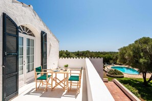 A terrace with a table and chairs, a pool, and a view of the landscape.