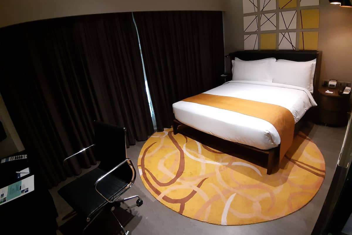 A hotel room with a bed, a desk, and a chair.