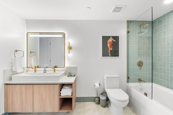 A modern bathroom with a large mirror, dual sinks, a toilet, and a glass-enclosed shower. - Nomada Residences - Downtown (Miami)