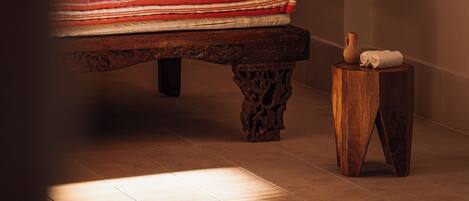A spa area with a wooden bench, a small wooden stool, and a tiled floor.