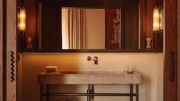 Une salle de bain moderne avec un meuble-lavabo en bois, un miroir et deux appliques murales.