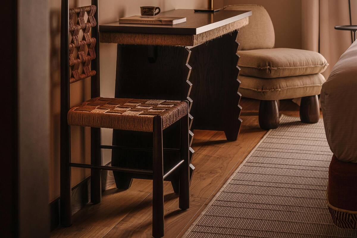 A cozy room with a wooden desk, a chair, a sofa, and a television mounted on the wall.