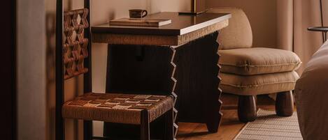 A cozy room with a wooden desk, a chair, a sofa, and a television mounted on the wall.