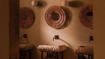 A bathroom with three sinks, each with a textured cover, and three wall-mounted mirrors with circular designs.