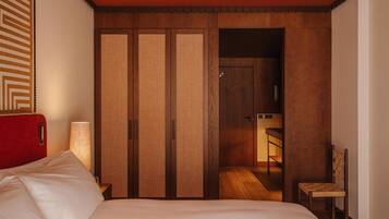 Una habitación de hotel con una cama, una silla, un armario de madera y una lámpara.