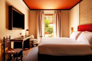 Ein Hotelzimmer mit Bett, Schreibtisch, Stuhl, Fernseher und Blick ins Freie.