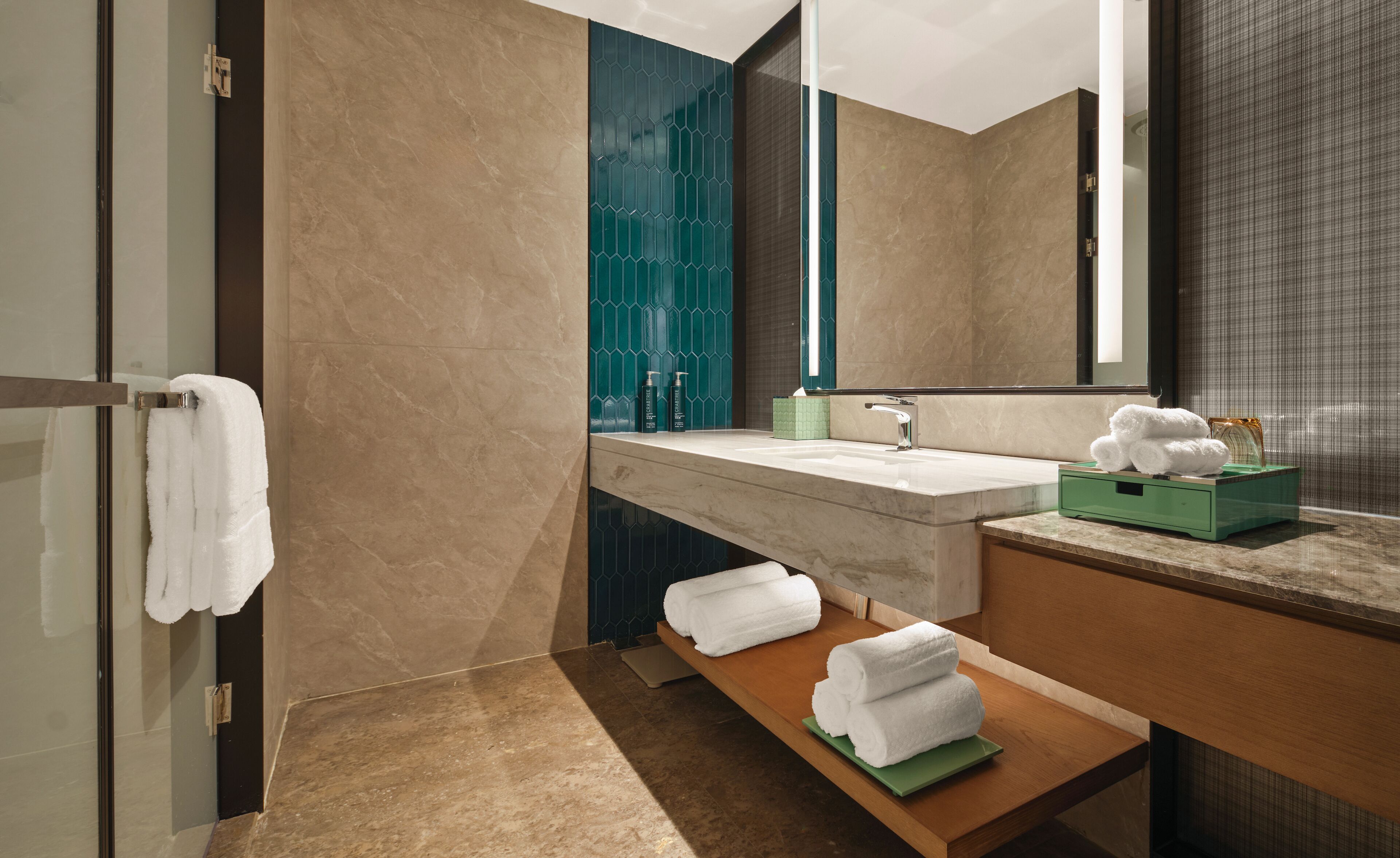 A modern bathroom with a marble vanity, a large mirror, and a wooden shelf with towels.