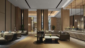 A modern hotel lobby with a seating area, a reception desk, and a large window. - DoubleTree By Hilton Zhengzhou East (Zhengzhou)