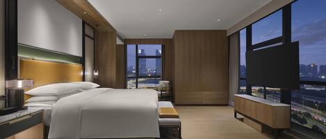 A modern hotel room with a large bed, a TV, and a city view.