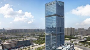 Un hotel moderno de rascacielos con fachada de vidrio, rodeado de un paisaje urbano cuidado.