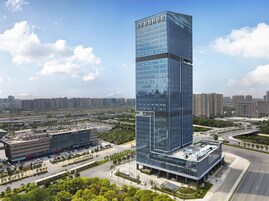 Un hotel moderno de rascacielos con fachada de vidrio, rodeado de un paisaje urbano cuidado.