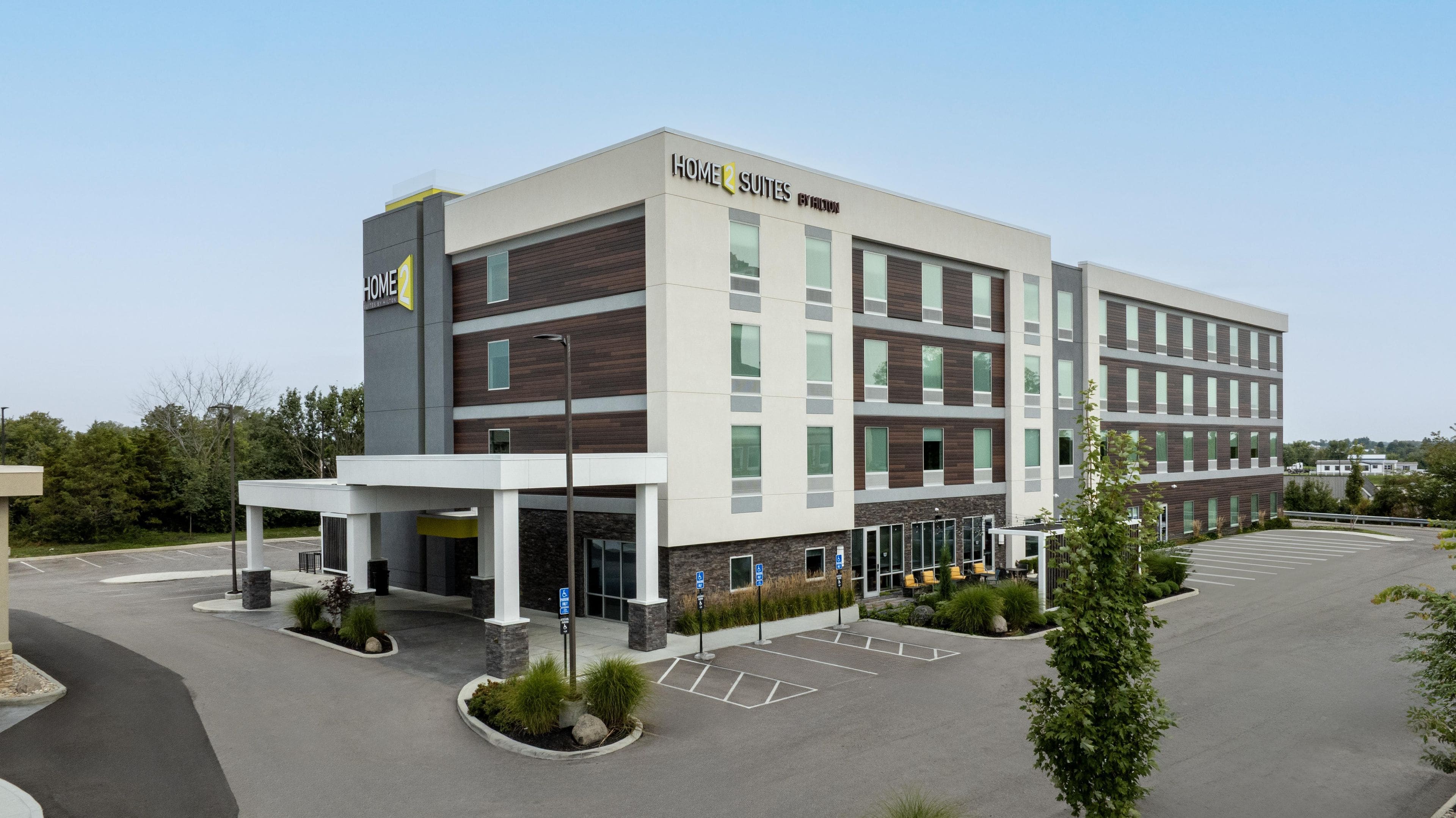 A multi-story hotel with a modern design, featuring a prominent sign for 'Home 2 Suites by Hilton.'
