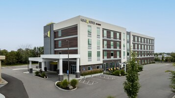 Un hotel moderno de varios pisos, con un letrero llamativo que dice 'Home 2 Suites by Hilton'.