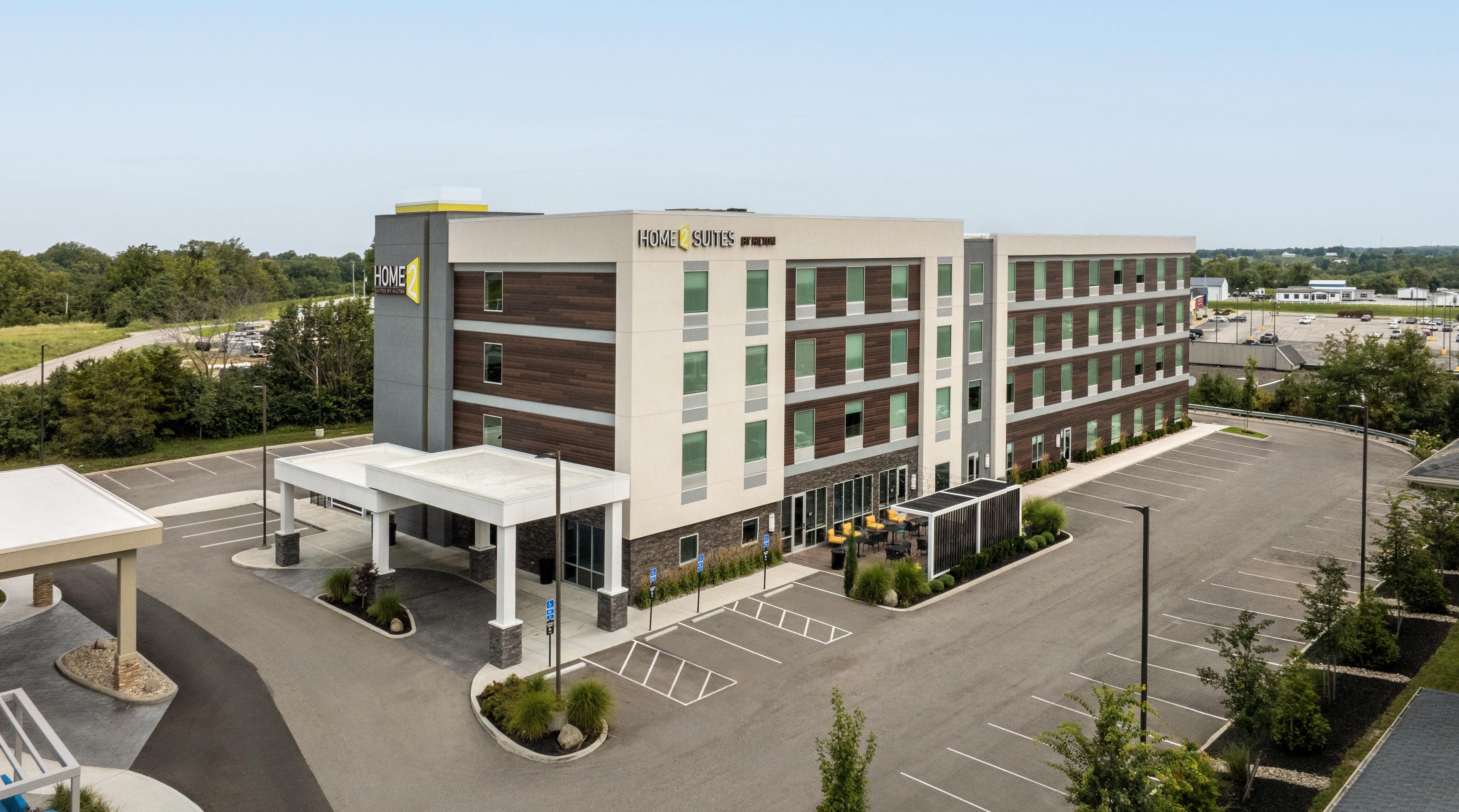 A multi-story hotel with a modern design, featuring a covered entrance and a parking lot.