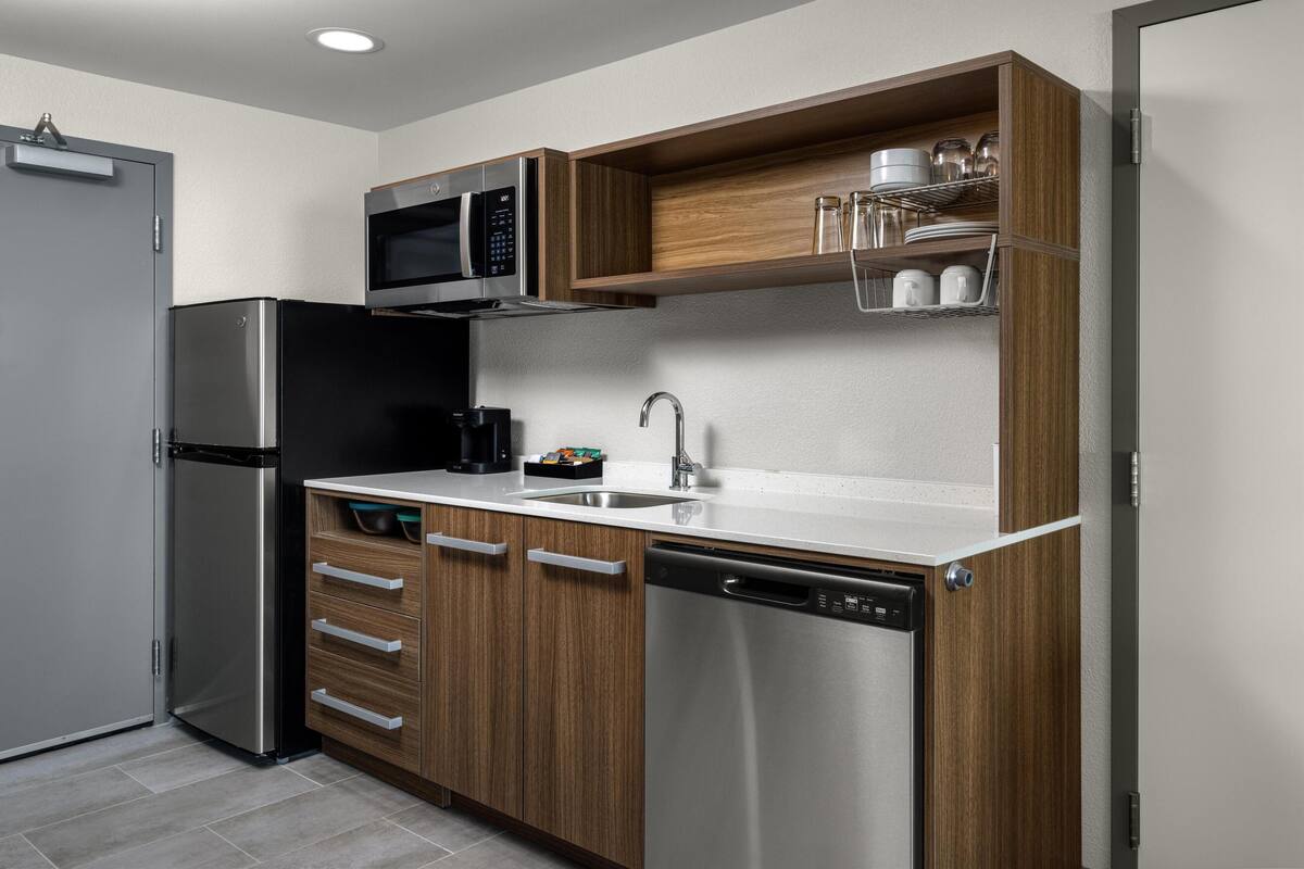 A modern kitchen with stainless steel appliances, wooden cabinetry, and a built-in microwave shelf.