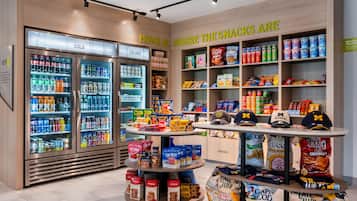 A snack and beverage section with refrigerated drinks, snack bars, and a display of branded caps.