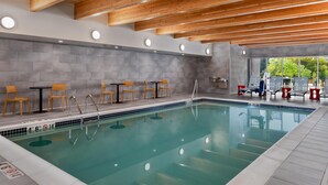 Ein Schwimmbecken mit Holzbalken, gefliesten Wänden und Sitzbereichen.