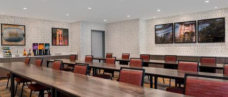 A conference room with long tables and chairs, framed pictures on the walls, and a patterned wallpaper.