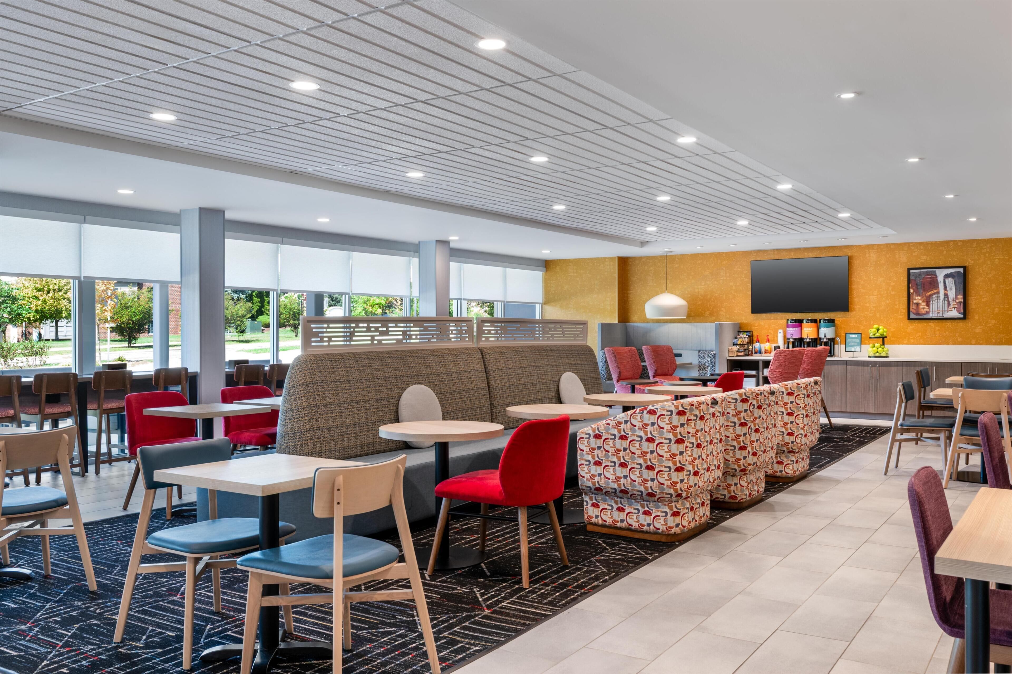 Eine moderne Hotelhalle mit Sitzbereichen, einer Bar und großen Fenstern.