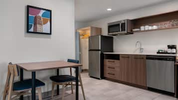 A modern kitchen with a dining table, chairs, a refrigerator, microwave, and a dishwasher.
