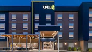 Un hôtel moderne avec une enseigne « HOME 2 », des places assises à l’extérieur et une entrée abritée.