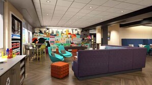 A modern lounge area with a purple sofa, teal chairs, and a bar area with colorful decor. - Tru By Hilton Huntsville Research Park Area (Huntsville)