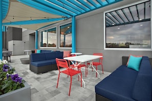 An outdoor patio with a blue sofa, red chairs, a white table, and a grey couch. - Tru By Hilton Huntsville Research Park Area (Huntsville)