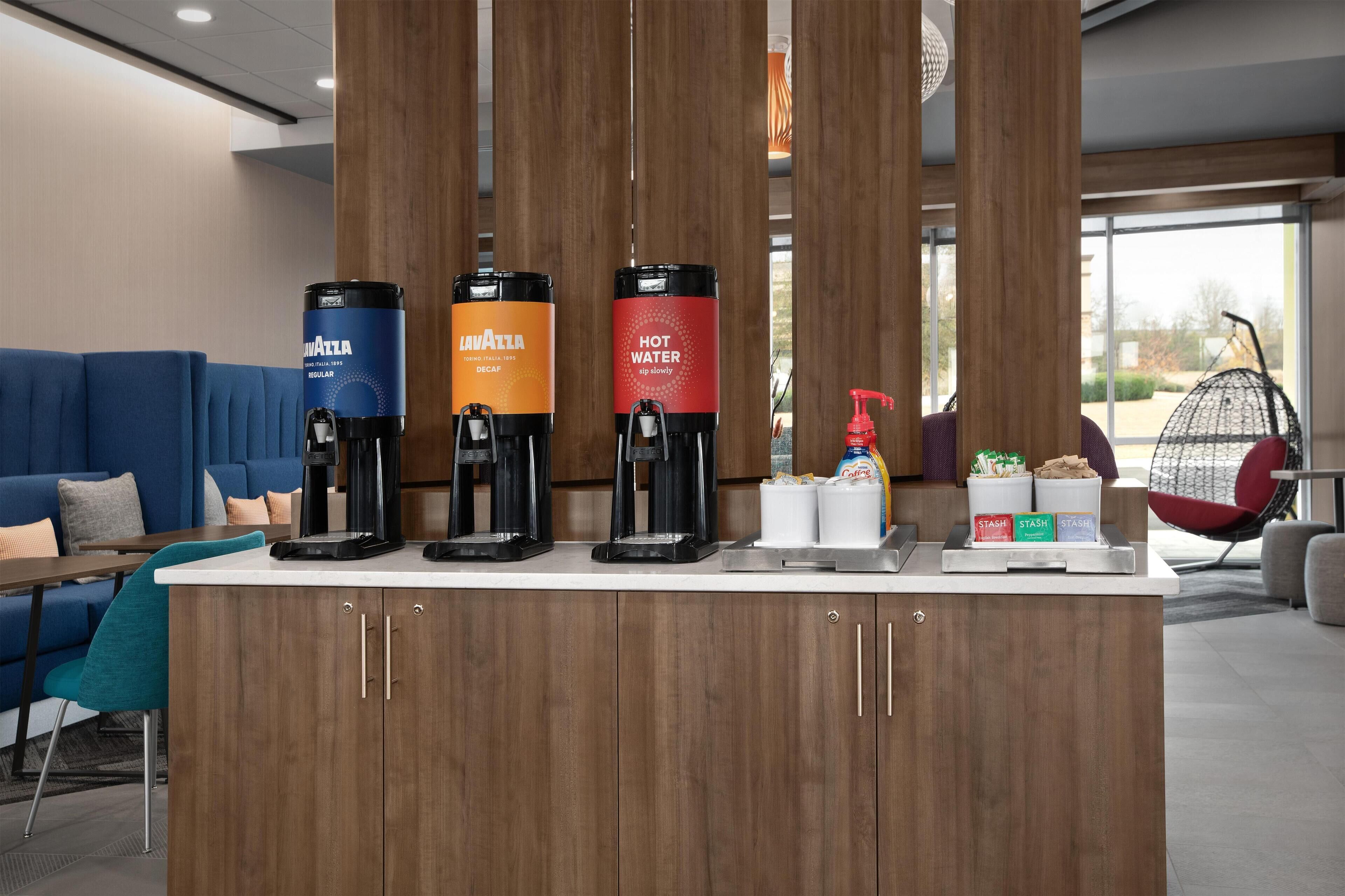 Ein Kaffee-Bereich mit drei Spendern, beschriftet mit 'Lavazza', 'Lavazza' und 'Heißwasser'.