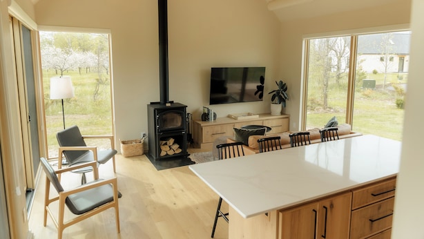 A modern kitchen with a large island, wooden cabinets, and a built-in stove.