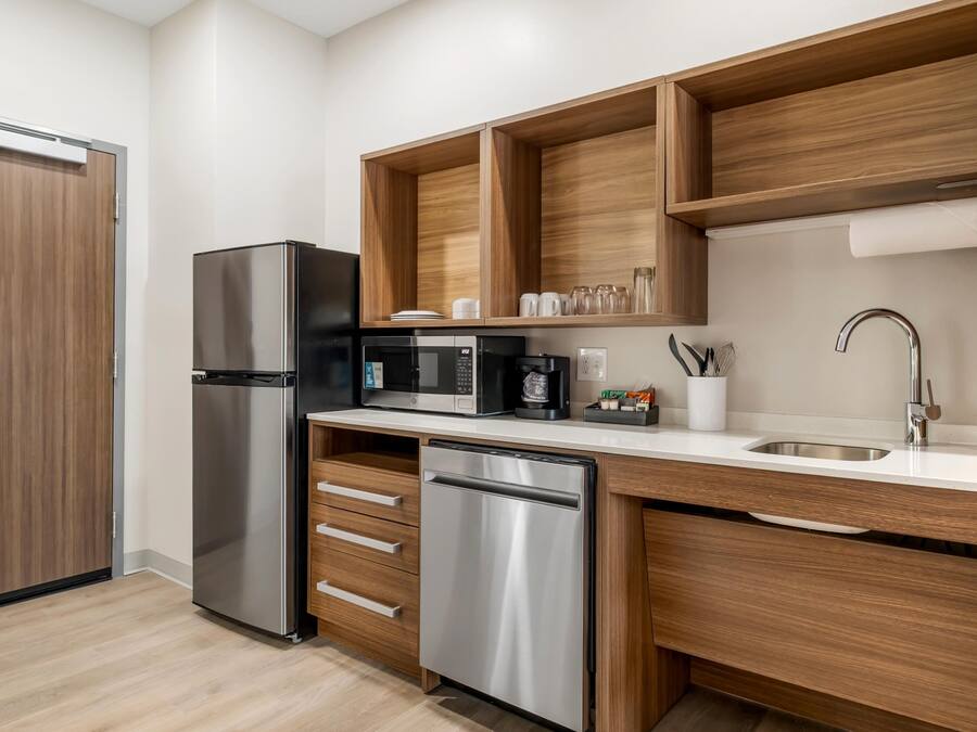 A modern kitchen with a stainless steel refrigerator, a built-in microwave, a coffee maker, and a dishwasher.