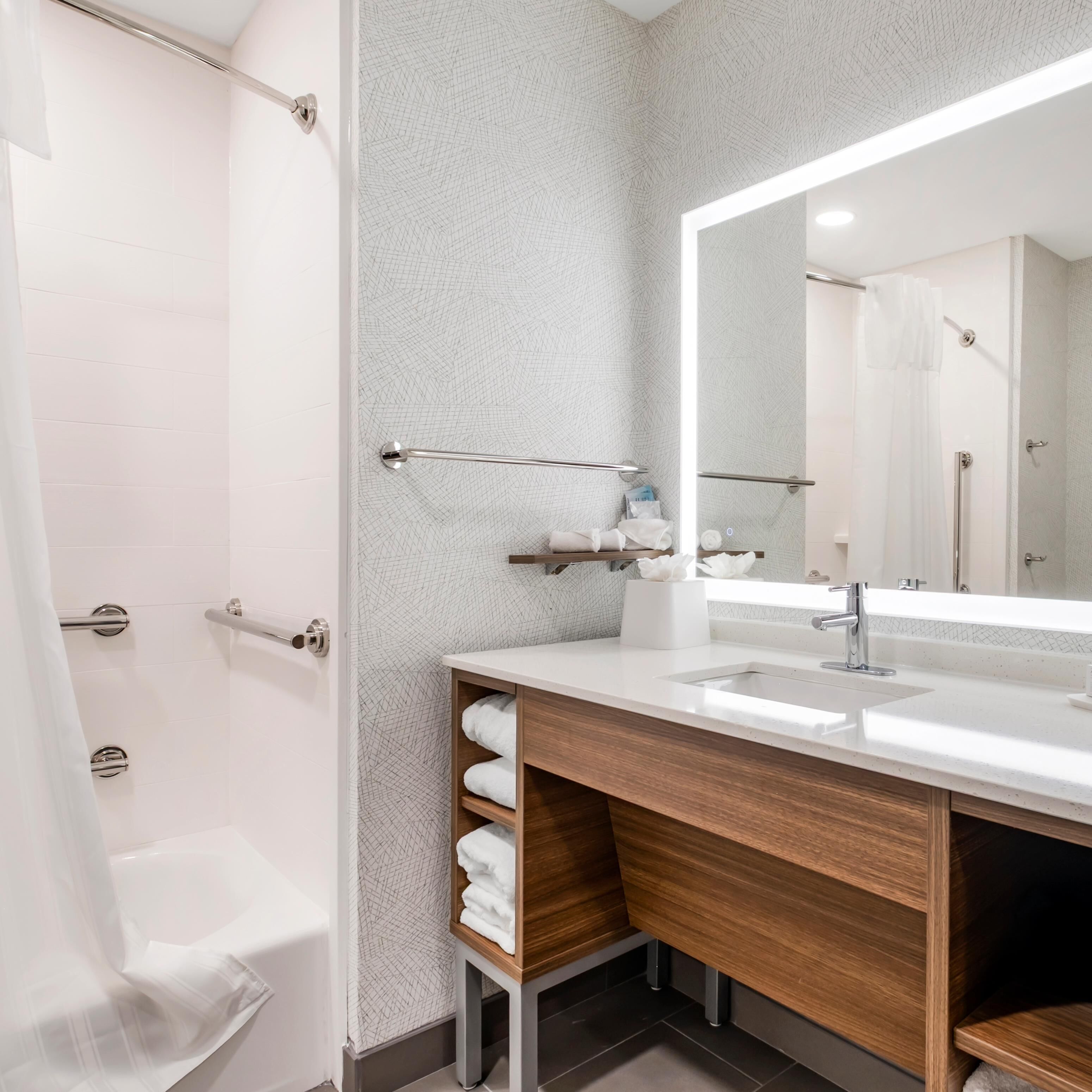 Un baño moderno con ducha, lavabo con espejo y perchero.