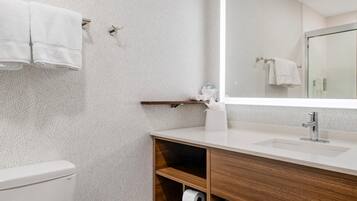 A modern bathroom with a toilet, a sink, a mirror, and a towel rack.