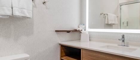 A modern bathroom with a toilet, a sink, a mirror, and a towel rack.