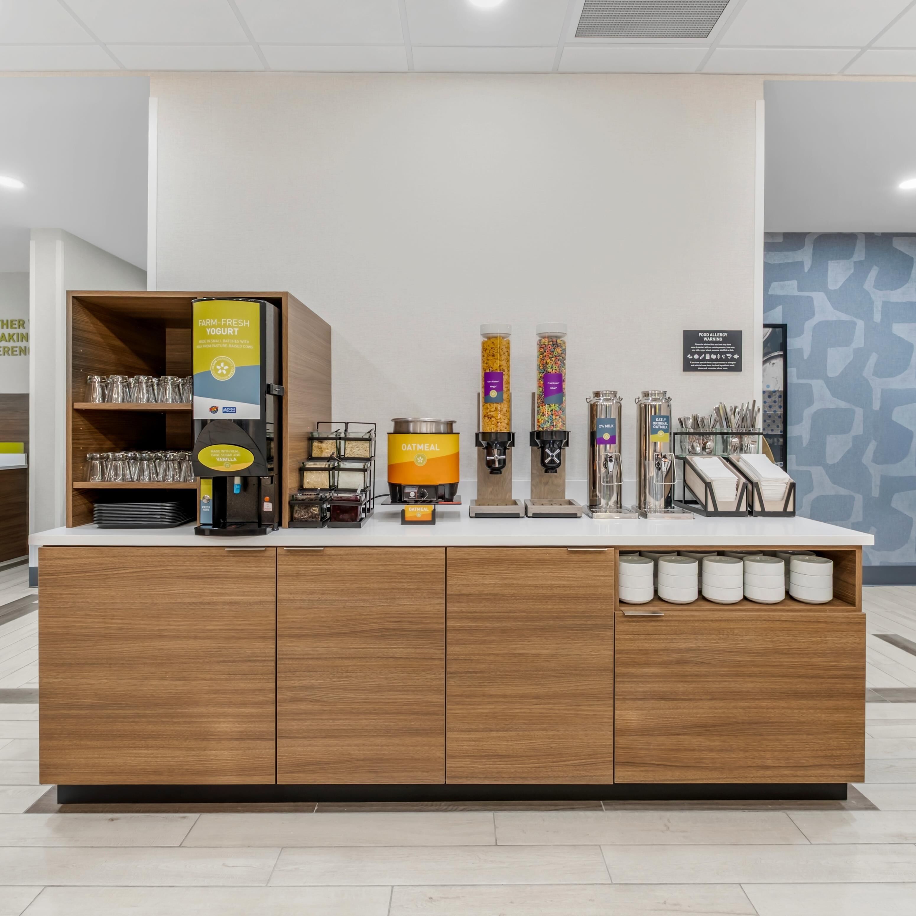 A self-service station with a coffee machine, a yogurt dispenser, and a cereal dispenser.