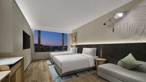 Een moderne hotelkamer met een groot raam, een bed, een bank en een bureau.