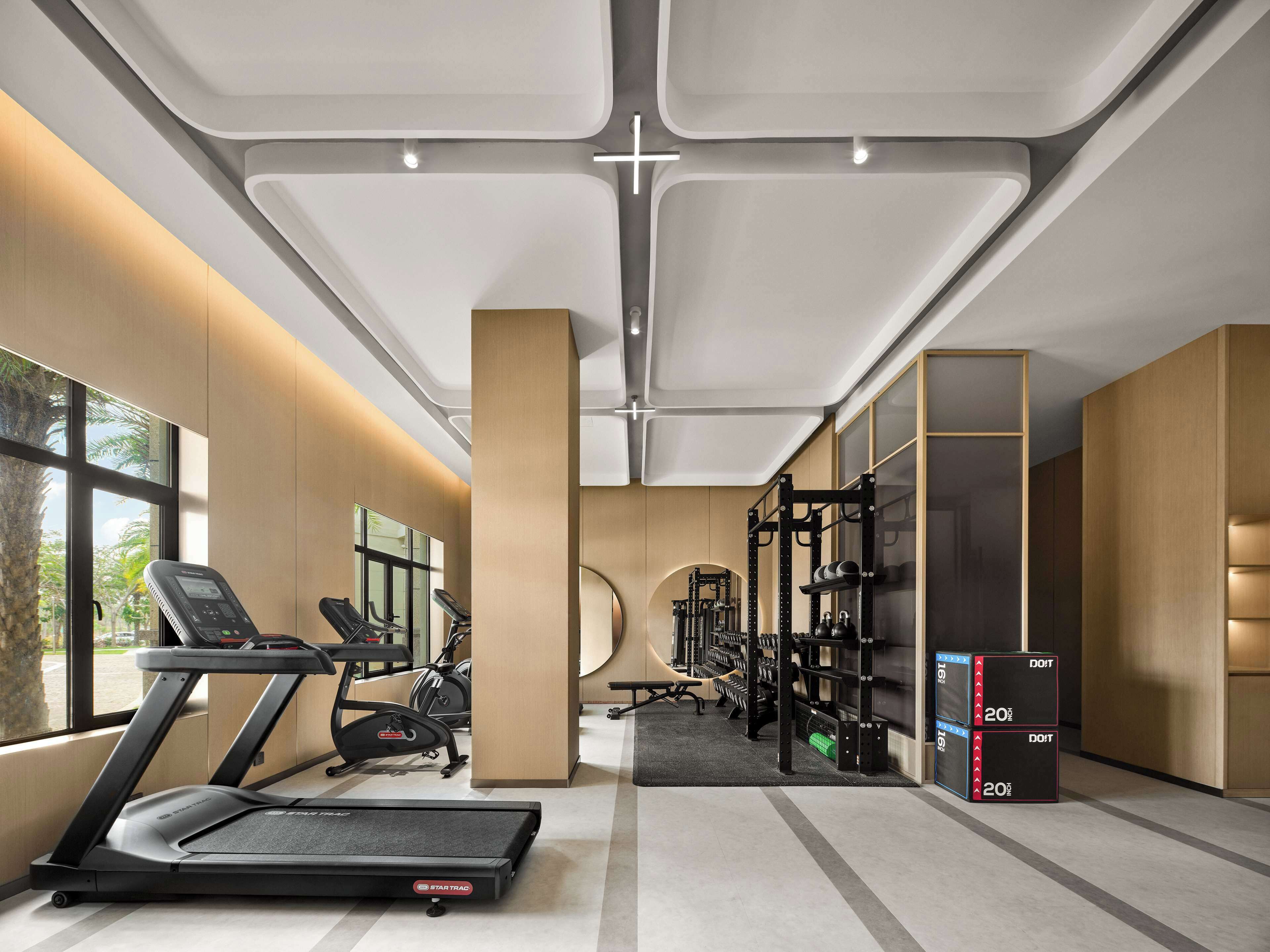 A modern gym with treadmills, elliptical machines, and weightlifting equipment.
