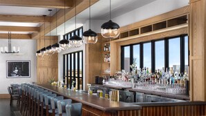 A bar area with a long counter, multiple bar stools, and hanging pendant lights. - Hotel Avail Rogers, Tapestry Collection By Hilton (Rogers)