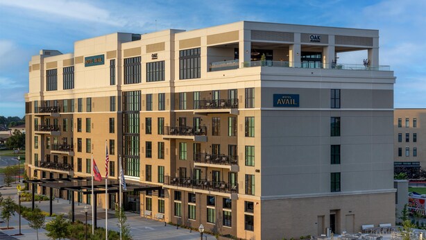 A multi-story hotel with balconies, a covered walkway, and a sign indicating it is the "OAK HOTEL AVAIL". - Hotel Avail Rogers, Tapestry Collection By Hilton (Rogers)