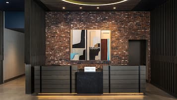 Een receptiebalie met een modern ontwerp, een bakstenen muur en abstracte kunstwerken erboven.