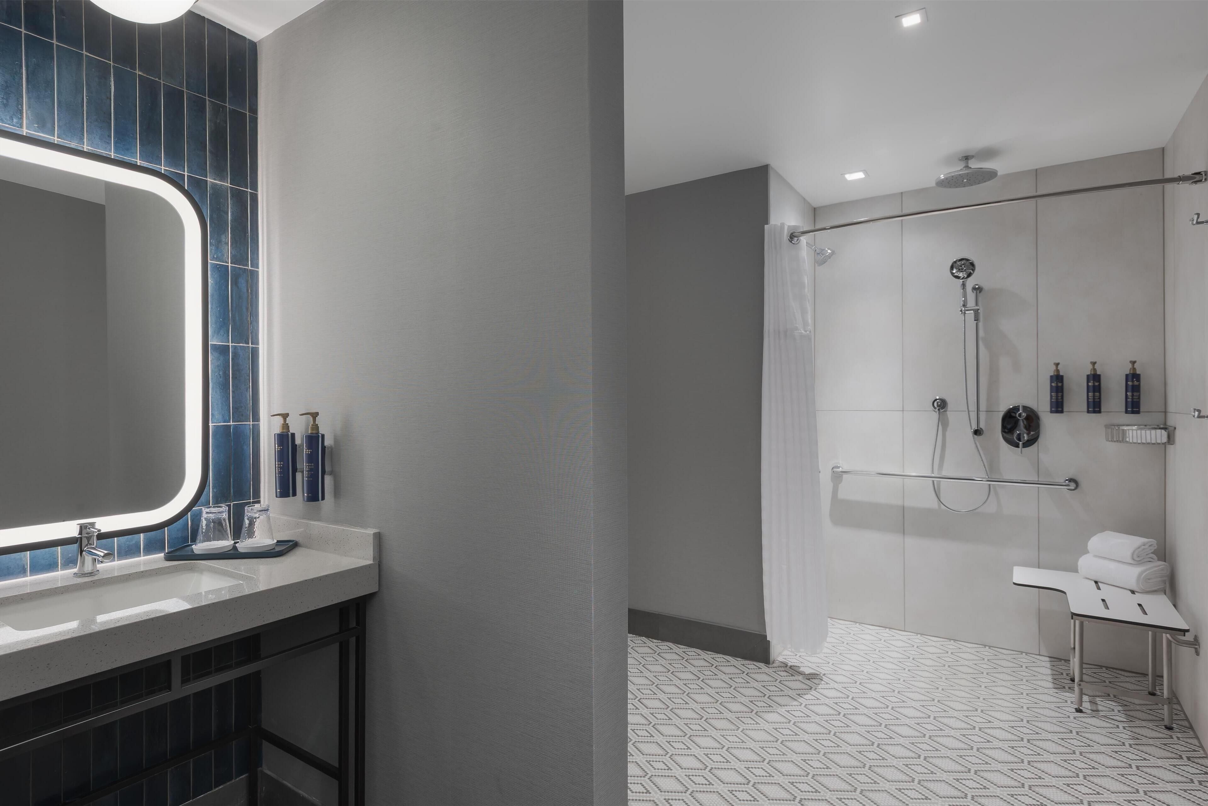 Un baño moderno con un espejo grande, zona de ducha y tocador con lavabo.