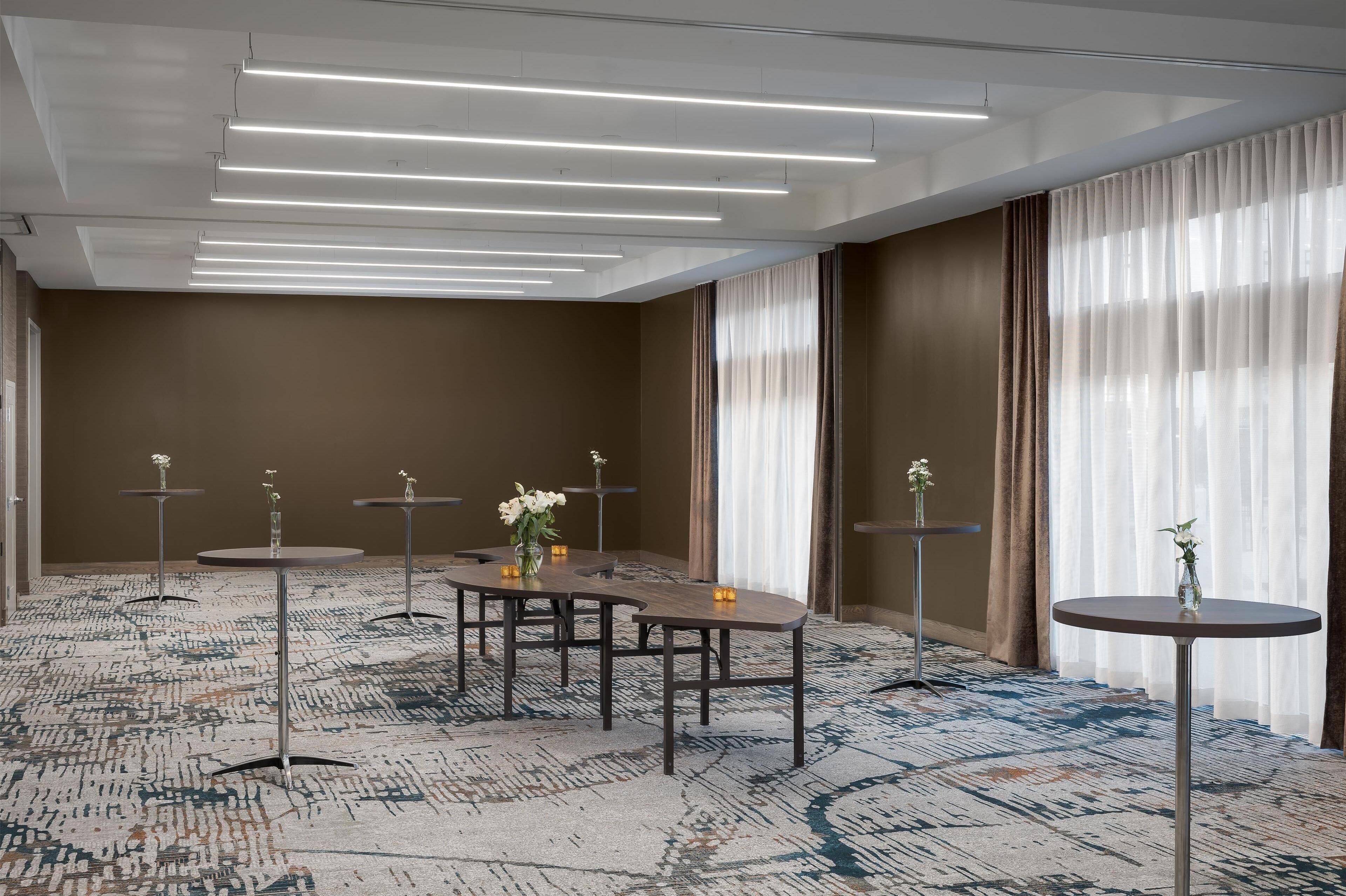 A conference room with a long table, round tables, and a patterned carpet.