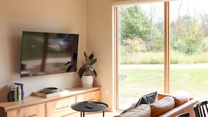 Un salon moderne avec une grande télévision, un canapé, une table basse et une plante en pot.