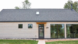 A modern building with a dark roof, a wooden facade, and a glass entrance.
