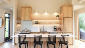 A modern kitchen with a central island, wooden cabinets, and a large window.