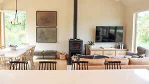 Una sala de estar moderna con un televisor grande, una chimenea, una zona de comedor y un sofá.