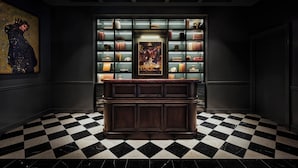 Rebedor amb un sòl de pissos, una taula de recepció de fusta fosca i una prestatgeria plena de llibres i objectes decoratius.