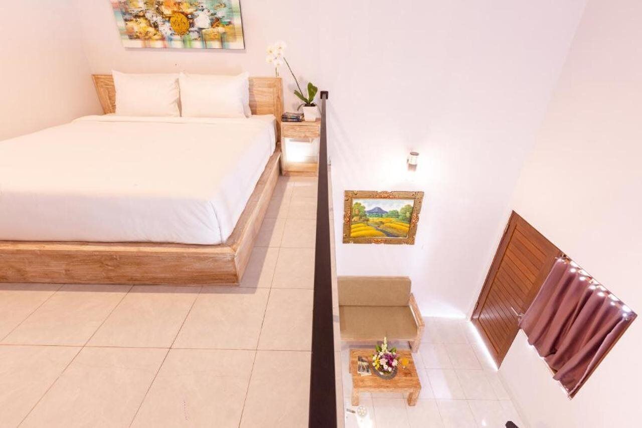 Een slaapkamer met een bed, nachtkastje, en een schilderij aan de muur.