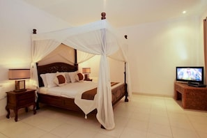 A four-poster canopy bed with a television on a wooden stand to the right. - Maisaba Seminyak Loft and Villas (Bali)