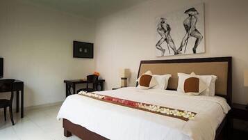 Een hotelkamer met een bed, een bureau, een stoel, een televisie en kunst aan de muur.