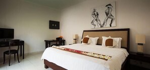 A hotel room with a bed, a desk, a chair, a television, and artwork on the wall. - Maisaba Seminyak Loft and Villas (Bali)